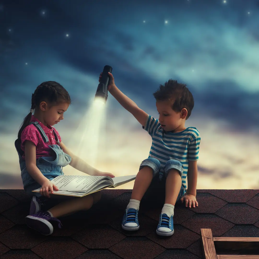 Two children discovering a story together by flashlight